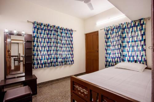 a bedroom with a bed with blue and white curtains at Whiteboard Homes Siolim in Siolim