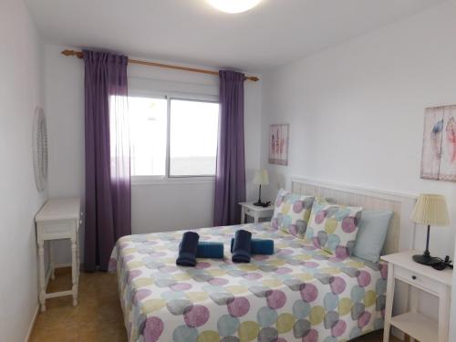 a bedroom with a bed with purple curtains and a window at El Rincón de Maruca Primero C in Gran Tarajal