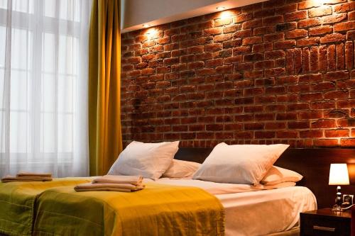 a bedroom with two beds and a brick wall at Hotel Artus - Old Town in Gdańsk