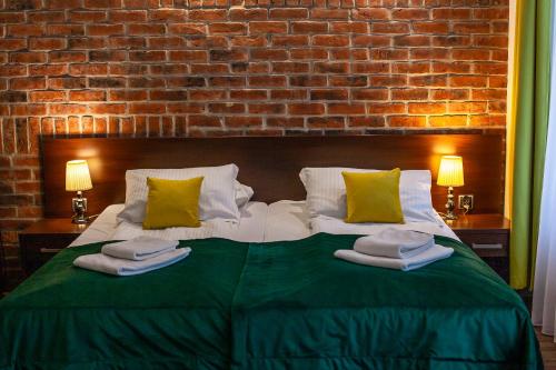 sypialnia z dużym łóżkiem z zieloną pościelą i poduszkami w obiekcie Hotel Artus - Old Town w Gdańsku
