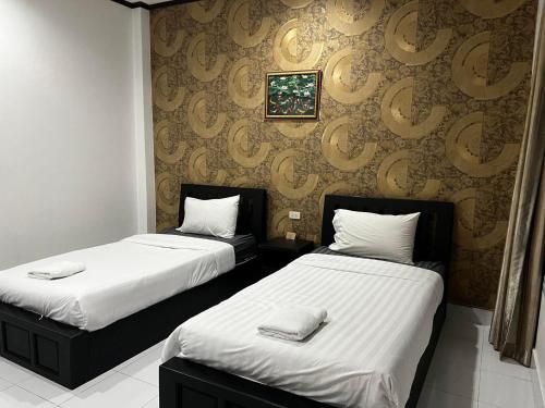 2 bedden in een hotelkamer met witte lakens bij บ้านบัวรีสอร์ท in Chiang Rai