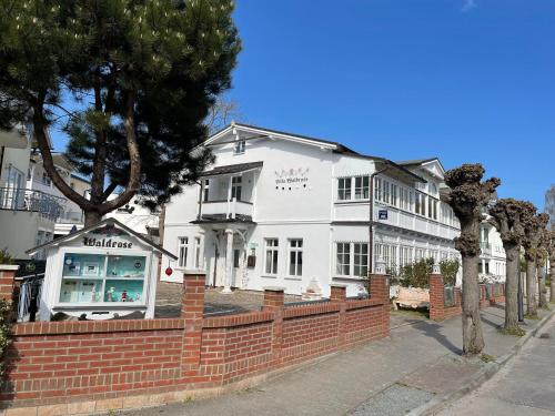 a white building with a brick fence in front of it at Villa Waldrose in Binz