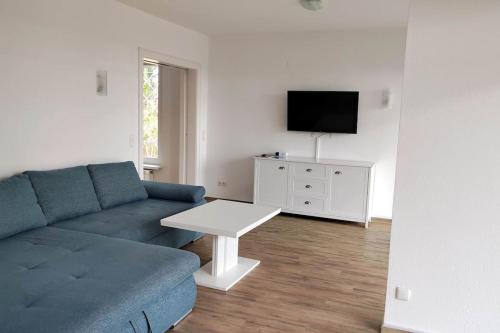 salon z niebieską kanapą i białym stołem w obiekcie Erdgeschoss Wohnung mit Garten w mieście Scharbeutz