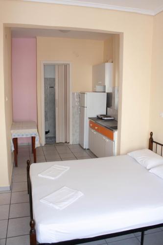 a bedroom with a white bed and a kitchen at Hermes in Paralia Katerinis
