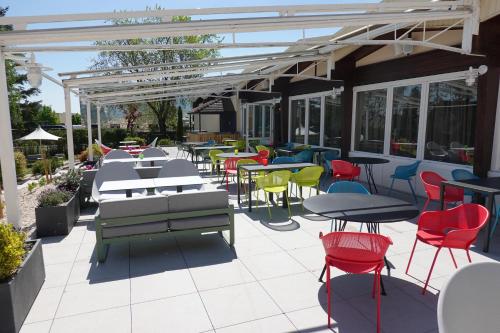 a patio with tables and colorful chairs and tables at Novotel Dijon Sud in Marsannay-la-Côte
