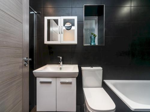 a bathroom with a toilet and a sink and a tub at Pass the Keys Modern Apartment 2 Minute Walk From Station in Surbiton