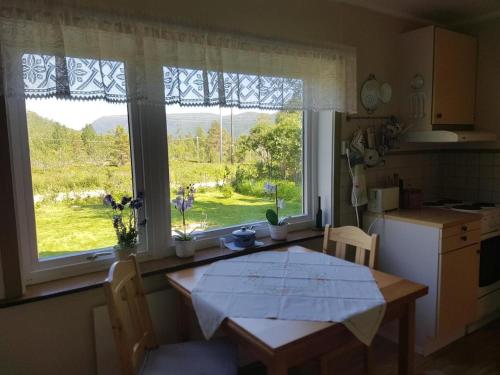 a kitchen with a table and a large window at Elvestua house in nature in Gibostad