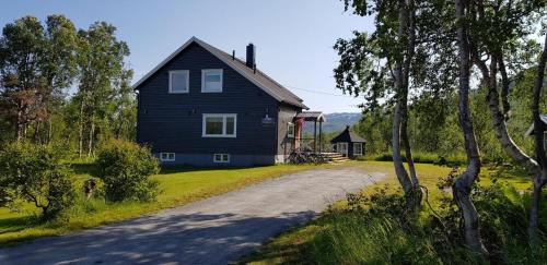 una casa negra al lado de una carretera en Elvestua house in nature, en Gibostad