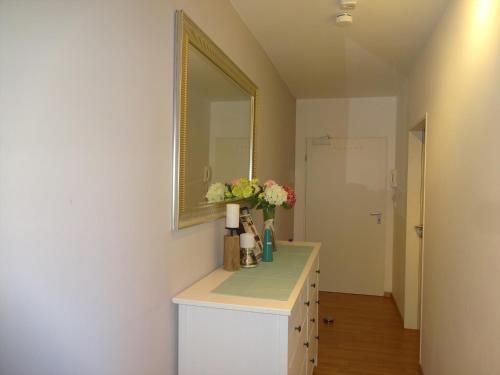 a bathroom with a vanity with a mirror and flowers at Moderne Wohnungen am Bahnhof Dachau mit direkter S-Bahn Verbindung nach München in Dachau