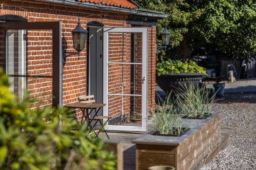 an open door of a brick building with plants at Norsminde Kro Anneks in Odder