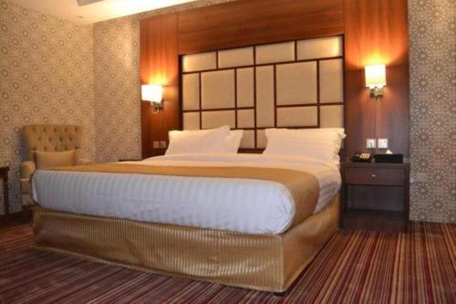 a bedroom with a large bed with a wooden headboard at QUIET Jeddah Al Hamra in Jeddah
