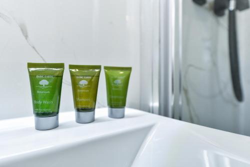 three bottles of green products sitting on a bathroom sink at Windmill Villa in Warsop