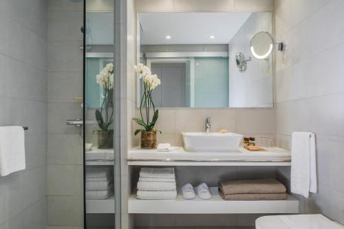 a white bathroom with a sink and a mirror at Alion Beach Hotel in Ayia Napa