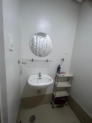 uma casa de banho branca com um lavatório e um espelho em Suite in the City em Manila