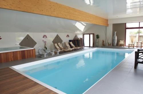 a large swimming pool in a living room with a large blue pool at Domaine de Kerzuat in Plouarzel