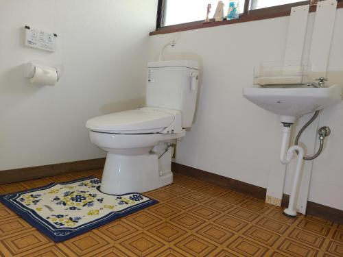 a bathroom with a toilet and a sink at ゲストハウス陽だまりの宿 in Tomi