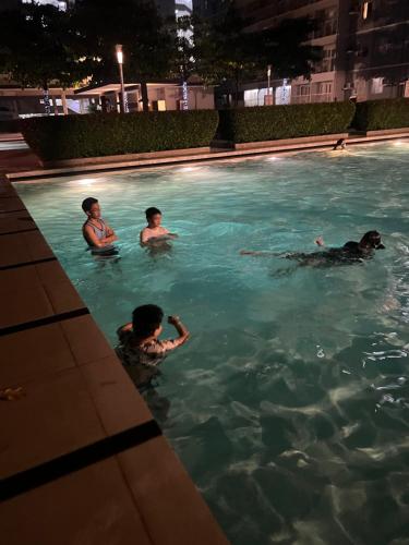 três pessoas a nadar numa piscina à noite em Suite in the City em Manila