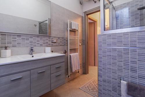 baño con lavabo y ducha con azulejos azules en Casa Maria en La Maddalena