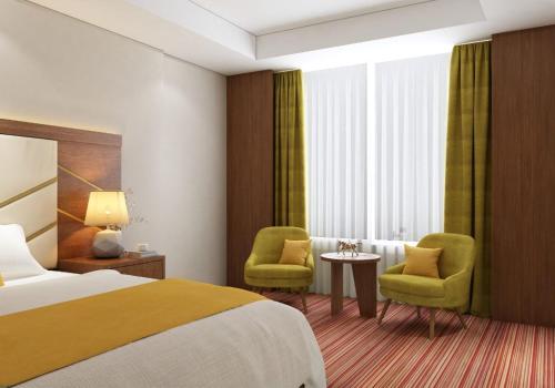 um quarto de hotel com uma cama e duas cadeiras em QUIET Jeddah Al Hamra em Jeddah