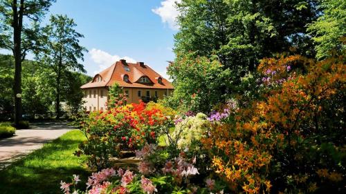 a garden with flowers in front of a house at Rezydencja Grawert Boutique & Spa in Lądek-Zdrój