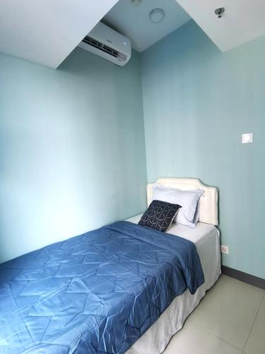 a bedroom with a bed with a blue wall at Benson Tower Surabaya Apartment 2BR by Le Ciel Hospitality in Lontar