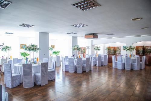 una habitación con sillas y mesas blancas en un edificio en Hotel Horezu en Horezu
