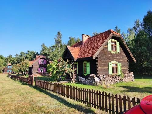a wooden house with a fence in front of it at Kiermusy Dworek nad Łąkami in Kiermusy
