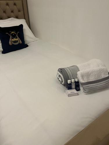 a white bed with a blanket and towels on it at TJ Homes - Luxury Studio Suite with Garden View - Next to tube station London in Ruislip