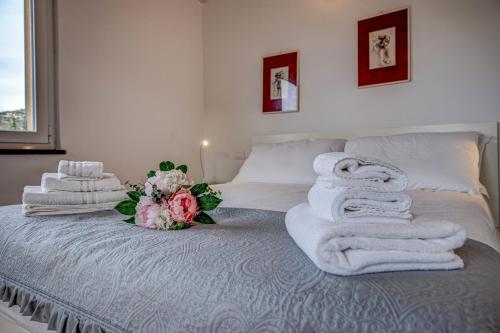 ein Bett mit Handtüchern und einem Blumenstrauß darauf in der Unterkunft CASA PARADISO Vista di lusso e tranquillità nello stesso posto in Camogli
