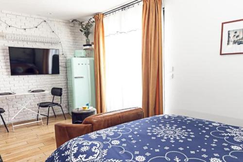 Le Studio de la Rue Mounié في اُنتوني: غرفة نوم بسرير ازرق وغرفة معيشة