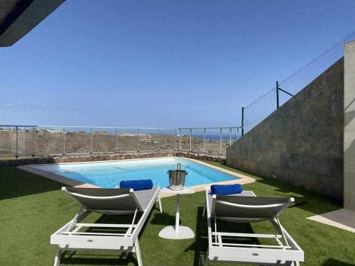 a patio with a table and chairs next to a swimming pool at Villa Calm Ocean views by Infinity Summer in La Playa de Arguineguín