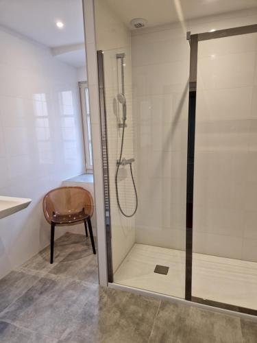 a shower with a glass door and a chair in a bathroom at Hôtel Patricia - Strasbourg Hyper Centre in Strasbourg