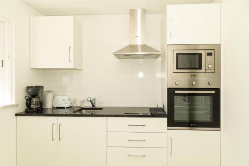 a kitchen with white cabinets and a microwave at O Pinhal do Avô - BY BEDZY in Almancil