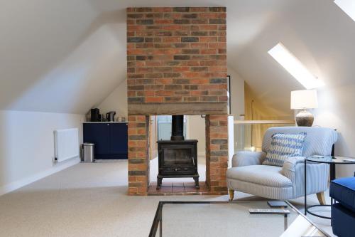 a living room with a brick fireplace and a chair at The Willow Apartment - Greentrees Estate in Haywards Heath