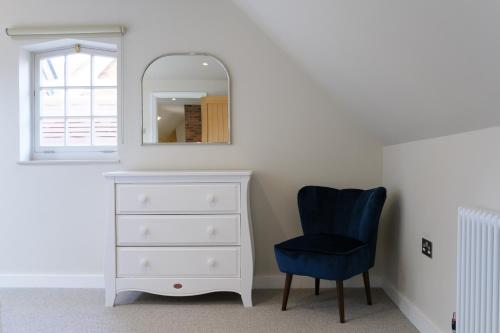 a bedroom with a dresser and a blue chair at The Willow Apartment - Greentrees Estate in Haywards Heath