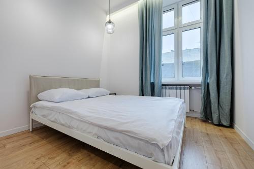 a bedroom with a bed with white sheets and a window at Piotrkowska Street III by LookAp in Łódź