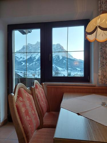 a dining room with a table and two chairs and windows at Landhaus Gerber in Lermoos