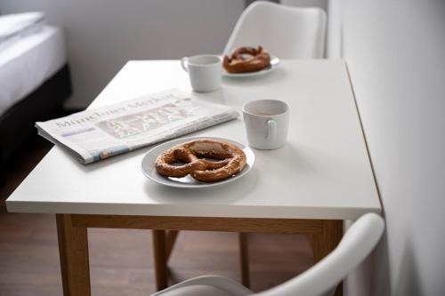 two donuts on a table with two cups and a book at apartmenthaus international in Munich
