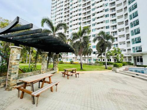 two picnic benches in a park with a large building at Cozy Place Anuva Residences in Manila