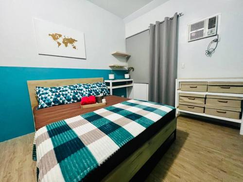 ein Schlafzimmer mit einem Bett mit einer blauen und weißen Decke in der Unterkunft Cozy Place Anuva Residences in Manila