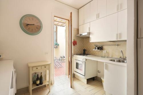 eine Küche mit weißen Schränken und einer Uhr an der Wand in der Unterkunft Belle Donne Historical Apartment - City Center in Florenz