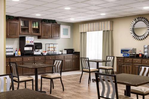 a waiting room with tables and chairs and a kitchen at Super 8 by Wyndham Savannah in Savannah