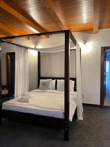 a canopy bed in a bedroom with a wooden ceiling at Agropensiunea Floare de Tei in Cărpiniş