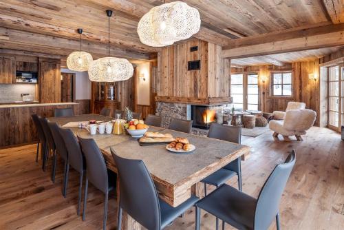 une salle à manger avec une grande table et des chaises en bois dans l'établissement Madame Vacances Chalet Les Sources de l'Isère, à Val dʼIsère