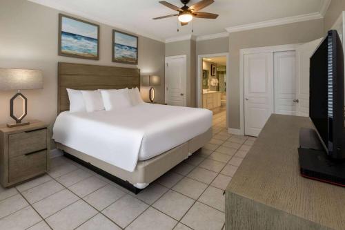 a bedroom with a large white bed and a television at Palm Beach Resort Orange Beach a Ramada by Wyndham in Gulf Shores