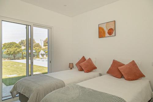 twee bedden in een kamer met een raam bij O PINHAL DO AVÔ in Almancil