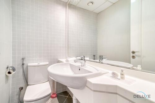 a bathroom with a sink and a toilet and a mirror at Harmonious 1BR at Al Shera Tower JLT by Deluxe Holiday Homes in Dubai