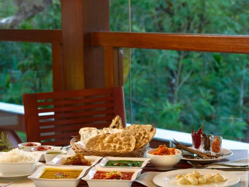 a table with plates of food and bowls of food at The Tamara Coorg in Kakkabe