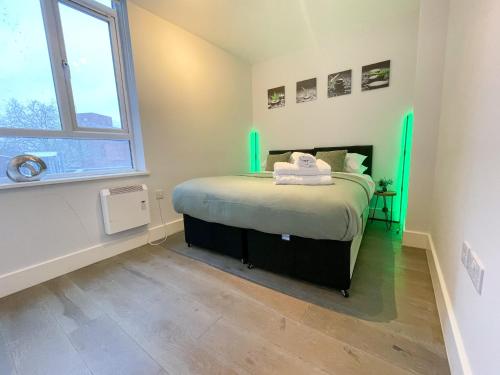 Super Cosy Apartment in The Heart Of Chelmsford في تشيلمسفورد: غرفة نوم بها سرير مع أضواء خضراء عليه