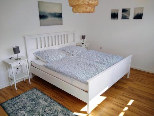 a white bed in a bedroom with two night stands at Ferienwohnungen Op der Kees in Irsch